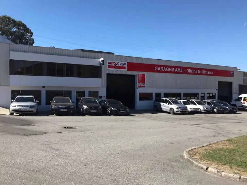 Pavilhão da Garagem AMZ na Rua de São Domingos, em Carvalhosa, com carros estacionados à frente